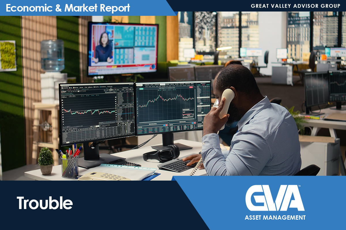 Trader on the phone at a desk with three monitors showing stock charts; busy trading room backdrop and 'Economic & Market Report' banner above.